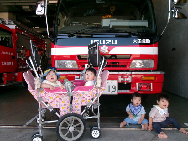 消防車の前に座っている子ども