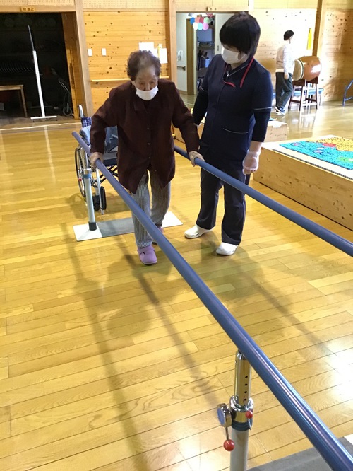 平行棒歩行中の利用者さんと職員