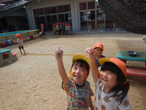 氷を太陽に照らしている子どもたち